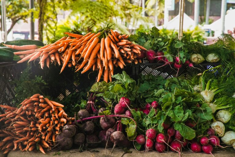 A vibrant display of fresh carrots, radishes, and greens at a local outdoor market.