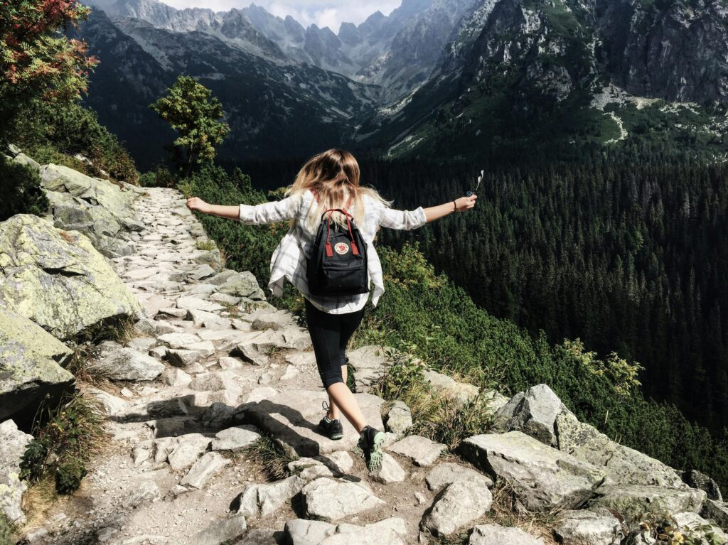 Woman hikes along rocky path in Vysoké Tatry, Slovakia. Embracing nature and freedom.